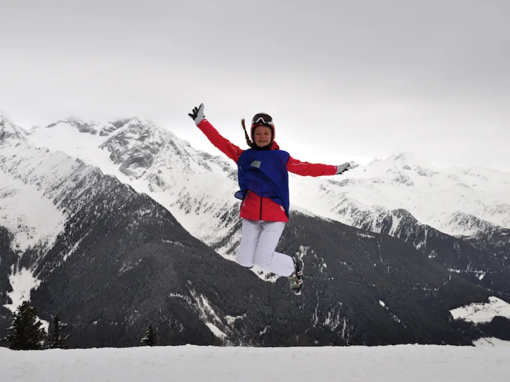 Person springt vor dem Bergpanorama in die Luft.